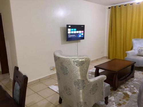 a living room with a chair and a tv at 3 Bedroom Retreat Apartment In Greatwall Gardens in Athi River