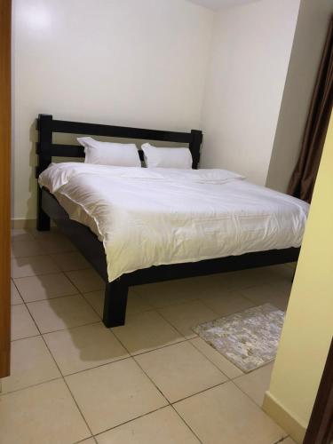 a bed with white sheets and pillows in a room at 3 Bedroom Retreat Apartment In Greatwall Gardens in Athi River