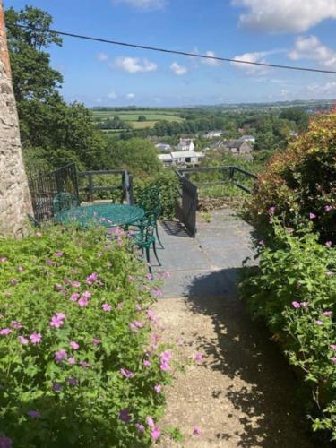 a garden with a green table and benches and flowers at Picturesque costal cottage, quite and peaceful in Saint Dogmaels