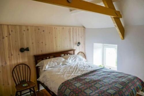 a bedroom with a bed and a wooden wall at Picturesque costal cottage, quite and peaceful in Saint Dogmaels