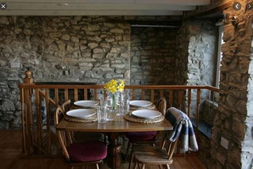 a wooden table in a room with a stone wall at Picturesque costal cottage, quite and peaceful in Saint Dogmaels
