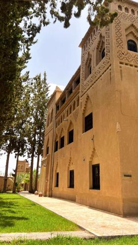 a large stone building with trees in front of it at Kasbah des cyprès in Skoura