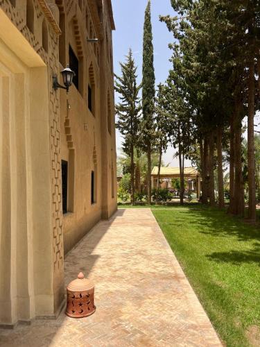 a walkway next to a building with a tree at Kasbah des cyprès in Skoura