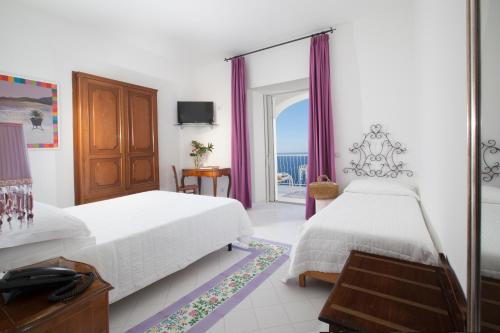 a bedroom with two beds and a view of the ocean at Hotel Smeraldo in Praiano