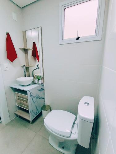 a bathroom with a toilet and a sink and a window at Apto TOP no Centro de Pelotas! in Pelotas