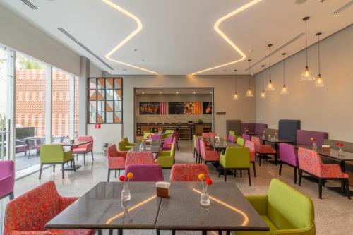 a restaurant with tables and chairs and windows at Hampton by Hilton Aguascalientes Downtown in Aguascalientes