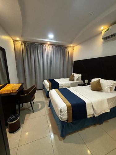 a hotel room with two beds and a piano at Ramis Serviced Apartments in Buraydah