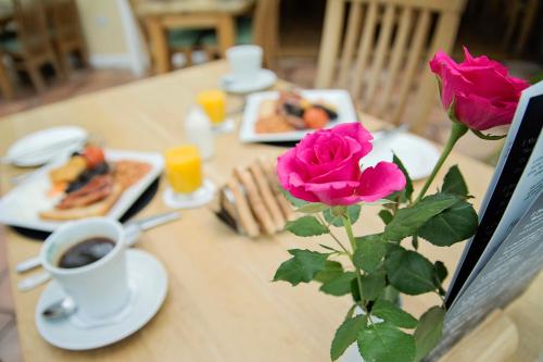 a table with a rose and a cup of coffee at Waveney House Hotel in Beccles