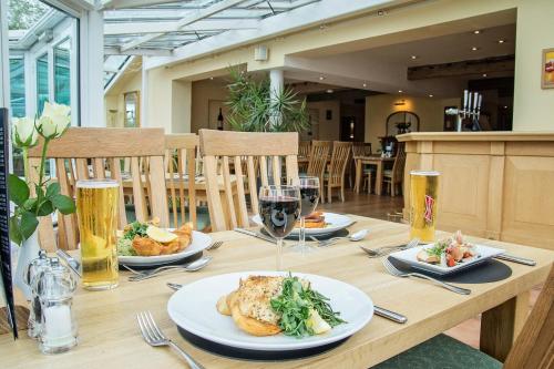 a wooden table with plates of food and glasses of beer at Waveney House Hotel in Beccles