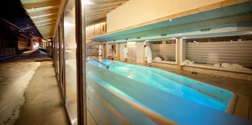a large swimming pool with blue water in a building at Bivio Hotel Plaza in Livigno