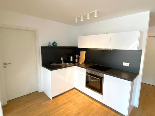 a kitchen with white cabinets and a black counter top at Timmenhus - neue Ferienwohnungen im historischen Bauernhaus in Timmendorfer Strand