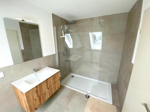 a bathroom with a sink and a shower with a mirror at Timmenhus - neue Ferienwohnungen im historischen Bauernhaus in Timmendorfer Strand