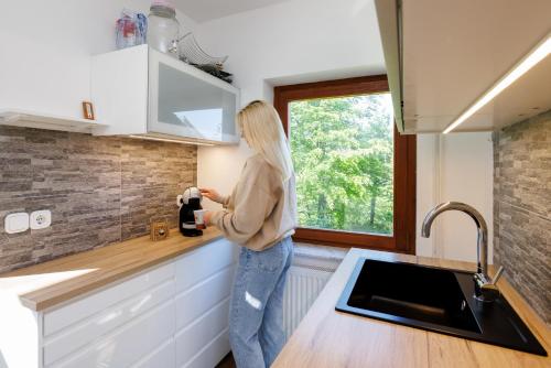 a woman standing in a kitchen looking out a window at Chalet Ana Bohinj in Bohinj