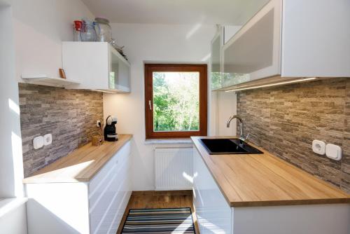 a kitchen with white cabinets and a brick wall at Chalet Ana Bohinj in Bohinj
