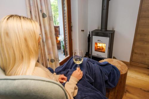 a woman sitting in a chair holding a glass of wine at Chalet Ana Bohinj in Bohinj