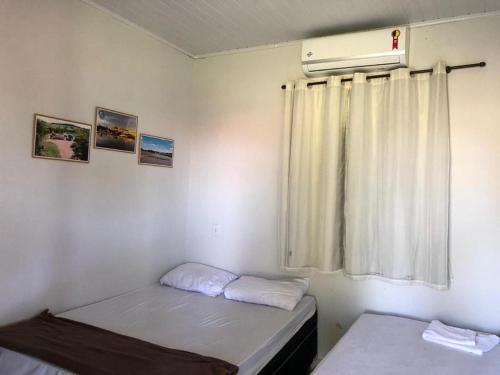 una piccola stanza con due letti e una finestra di Clube de pesca e pousada boa sorte a Itauçu