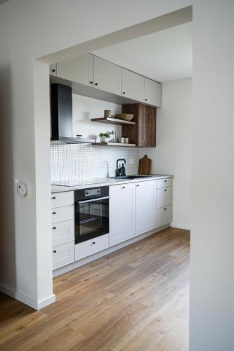 a white kitchen with wooden floors and white cabinets at Celý apartmán v rodinném domě s vanou a krbem in Česká Třebová