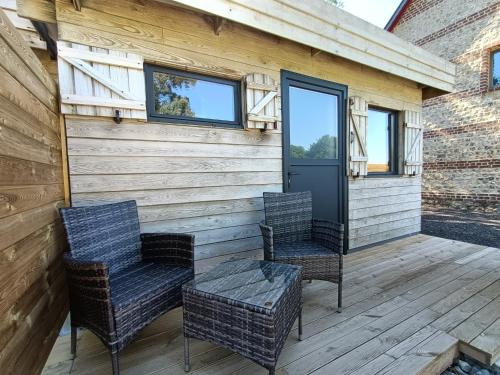 two chairs and a table on a porch with a door at Le Temps d'un Instant in Vattetot-sur-Mer