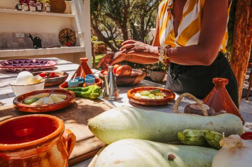 a woman preparing food on a table with vegetables at Hotel & Spa La Ferme El Dar in Marrakech