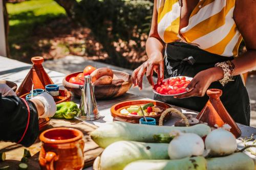 a person preparing food on a table with vegetables at Hotel & Spa La Ferme El Dar in Marrakech