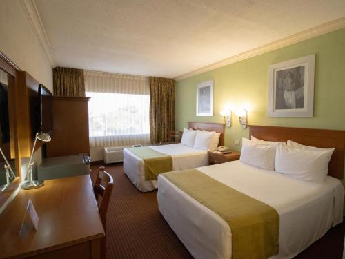 a hotel room with two beds and a television at Hotel Araiza Hermosillo in Hermosillo