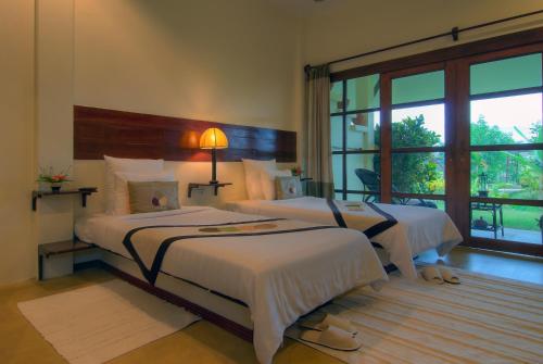 a bedroom with two beds and a large window at Maekok River Village Resort in Mae Ai