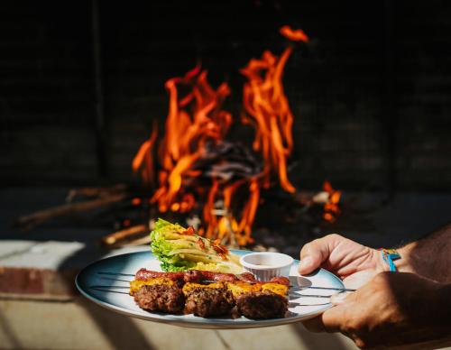 a person holding a plate of food in front of a fire at Hotel & Spa La Ferme El Dar in Marrakech