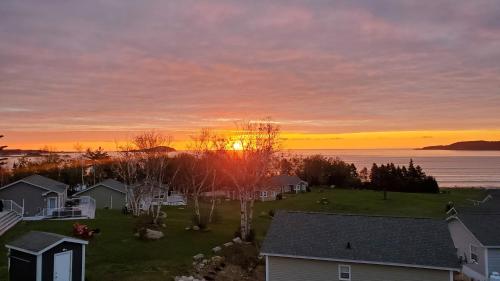 a sunset over a neighborhood with houses and the ocean at Ocean Breeze in Ingonish Beach