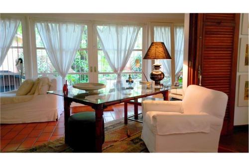 ペトロポリスにあるVilla do Lago Nogueiraのリビングルーム(ガラステーブル、白い椅子付)