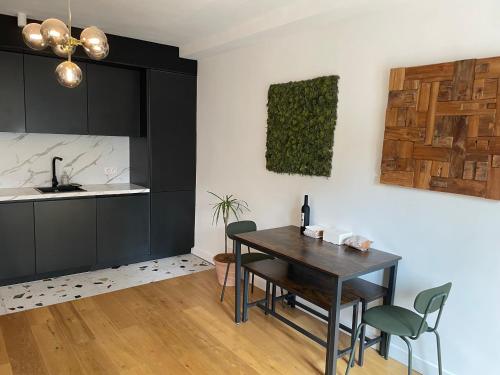 une cuisine avec des armoires noires, une table et des chaises dans l'établissement Appartement Élégant & Chic à Paris, à Paris