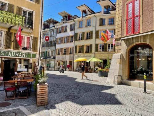 a man walking down a street in a city with buildings at La Bergerie in La Neuveville
