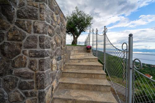 a stone wall with stairs and a fence at Vila Marigold in Opatija