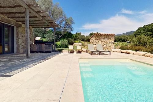 a swimming pool with two chairs and a house at ARGIALE - ARGHJALE in Figari