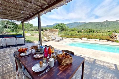 a table with a basket of food on it next to a pool at ARGIALE - ARGHJALE in Figari