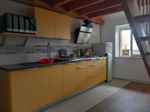 une cuisine avec des armoires jaunes et un réfrigérateur dans l'établissement Via Lactéa, à Saint-Goussaud