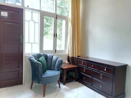 a living room with a blue chair and a window at Cherry Garden Terrace Hotel & Restaurant in Gilgit