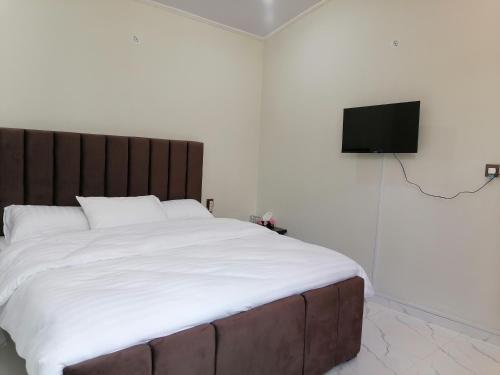 a bedroom with a large bed and a flat screen tv at Cherry Garden Terrace Hotel & Restaurant in Gilgit