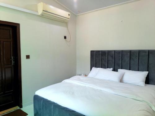 a bedroom with a large white bed with a gray headboard at Cherry Garden Terrace Hotel & Restaurant in Gilgit