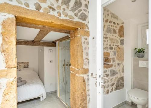 une salle de bain avec un lit et des toilettes dans une chambre dans l'établissement Aux Voûtes de Granit - 10 mn Lyon, à Pierre-Bénite