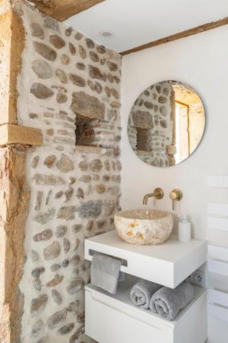 La salle de bains est pourvue d'un mur en pierre et d'un lavabo. dans l'établissement Aux Voûtes de Granit - 10 mn Lyon, à Pierre-Bénite