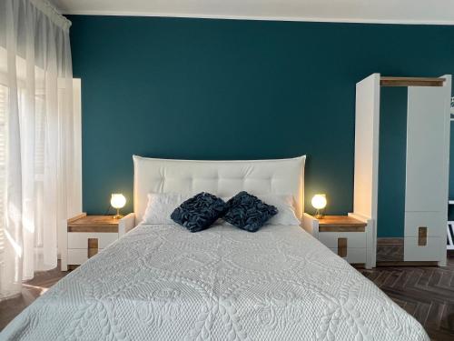 a bedroom with a white bed with two blue pillows at Casa Del Caval Bianco in Venaria Reale