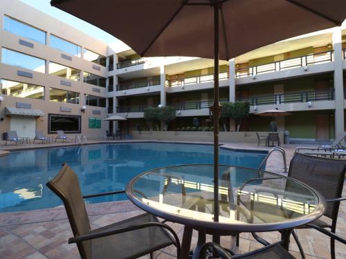 a table with an umbrella next to a swimming pool at Hotel Araiza Hermosillo in Hermosillo
