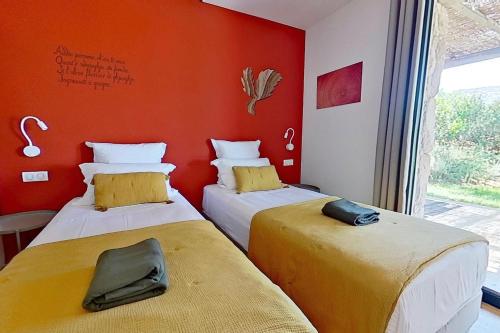 two beds in a room with an orange wall at ARGIALE - ARGHJALE in Figari