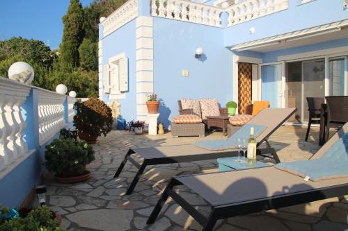 a patio with tables and chairs on a blue house at Villa Bettina 1st floor in Afionas