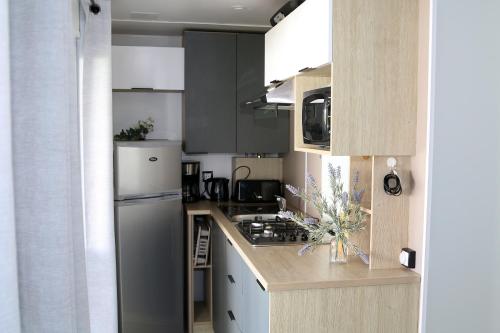 une cuisine avec une cuisinière et un réfrigérateur dans l'établissement Mobil-home Narbonne-Plage, à Narbonne-Plage