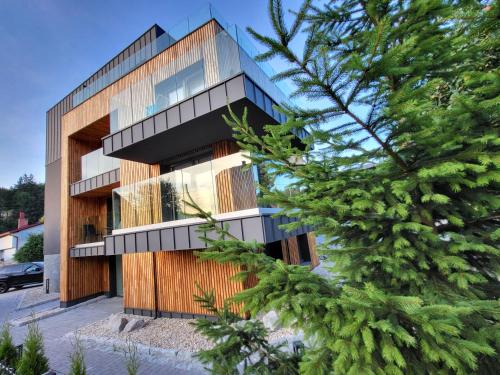 a building with a wooden facade with a tree at Apartamenty Nowa Osada - by VillaOlimpijska2 in Wisła