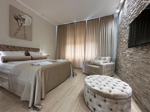 a bedroom with a bed and a chair in a room at Apartman Modena Novi Sad in Novi Sad