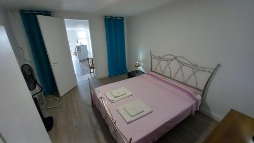 リスボンにあるAlvito Guest House - Comfortable room with private bathroomのベッドルーム1室(ピンクベッド1台、タオル2枚付)