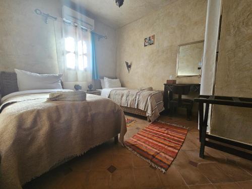 a bedroom with two beds and a mirror and a piano at Kasbah La Cigogne in Aït Ben Haddou