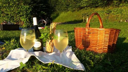 two glasses of wine and a basket and a bottle of wine at Gästehaus Riki Oberschmid in Steinbach am Attersee